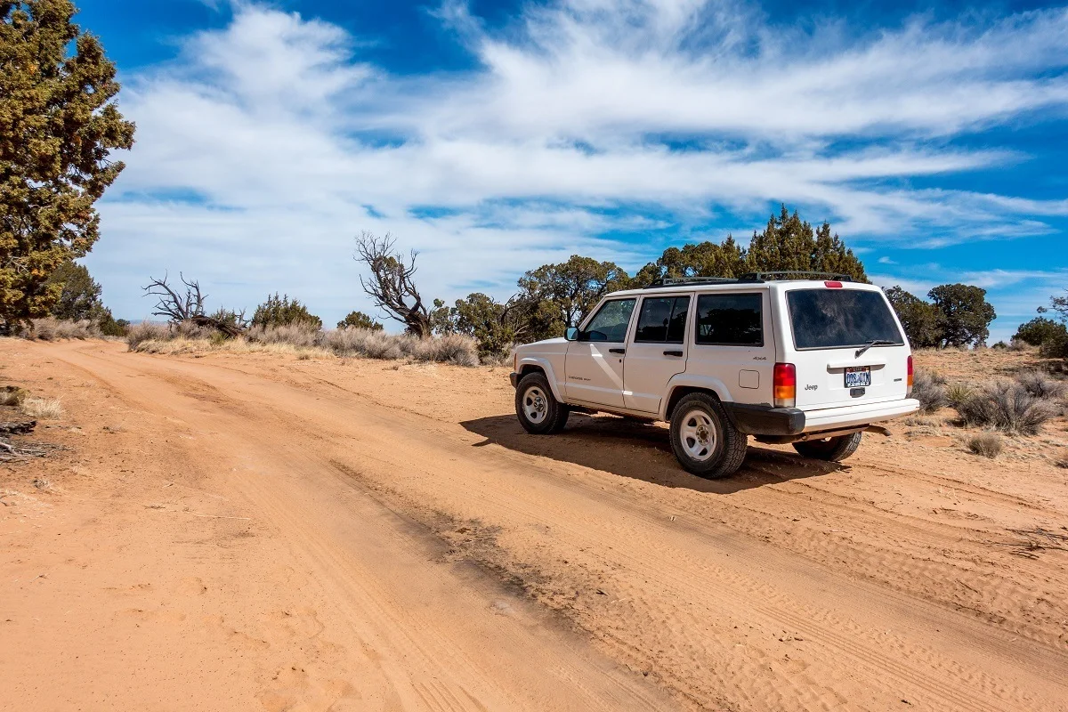 A white 4x4 jeep rental car on the sandy road to White Pocket