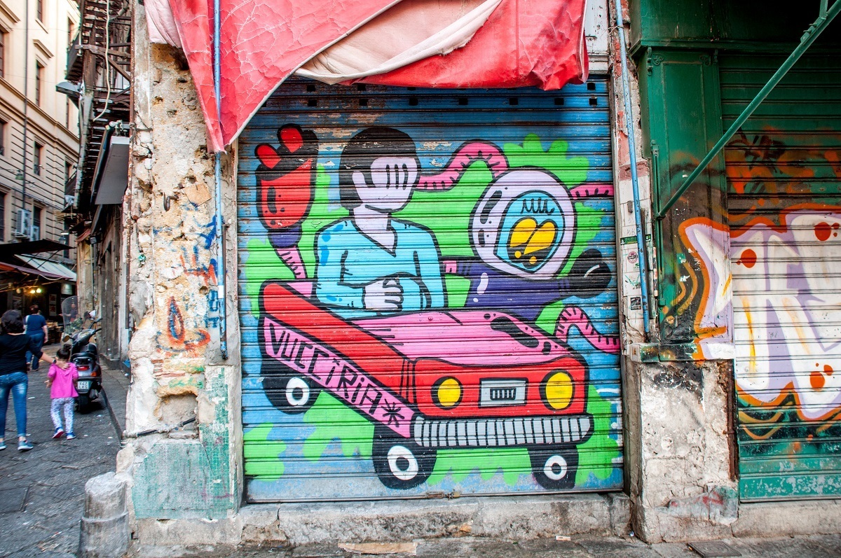 Street art mural of a person in a car labeled "Vucciria"