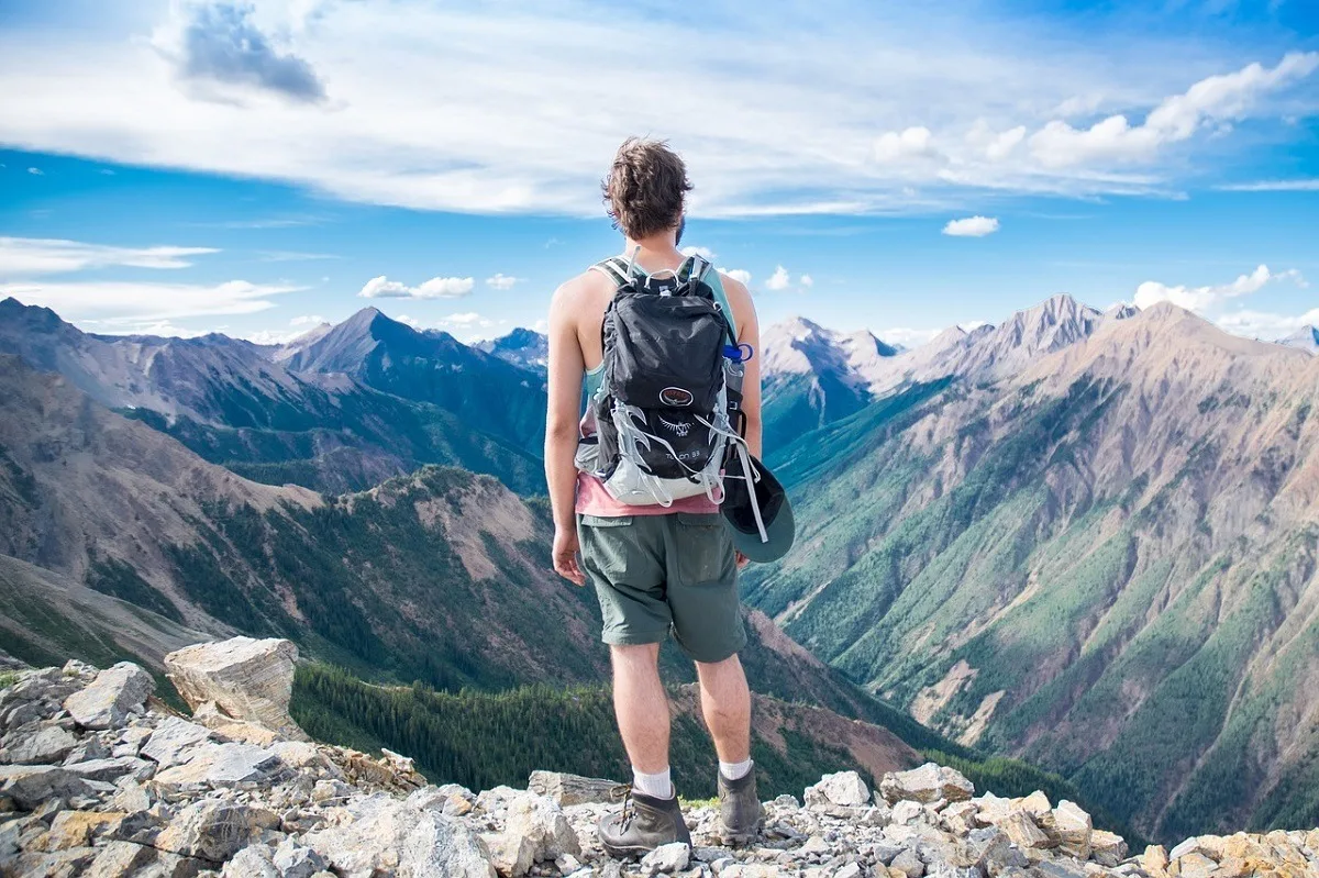 Person hiking on a rocky trail looking out at the mountains and a valley