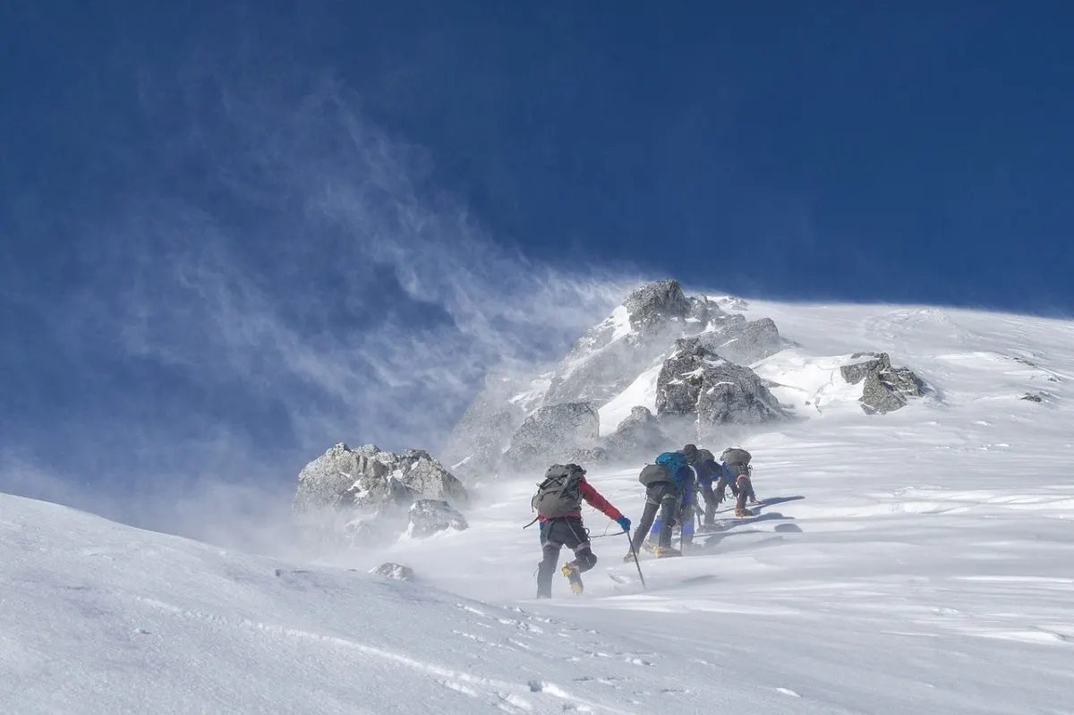 Group of people mountaineering up a steep, snowy mountain