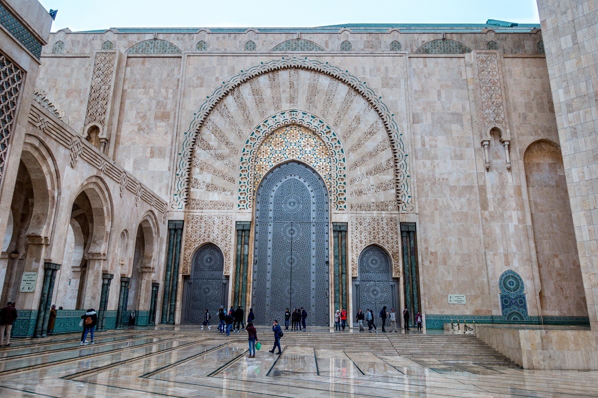 Visitors outside a large, decorative arch-shaped door.