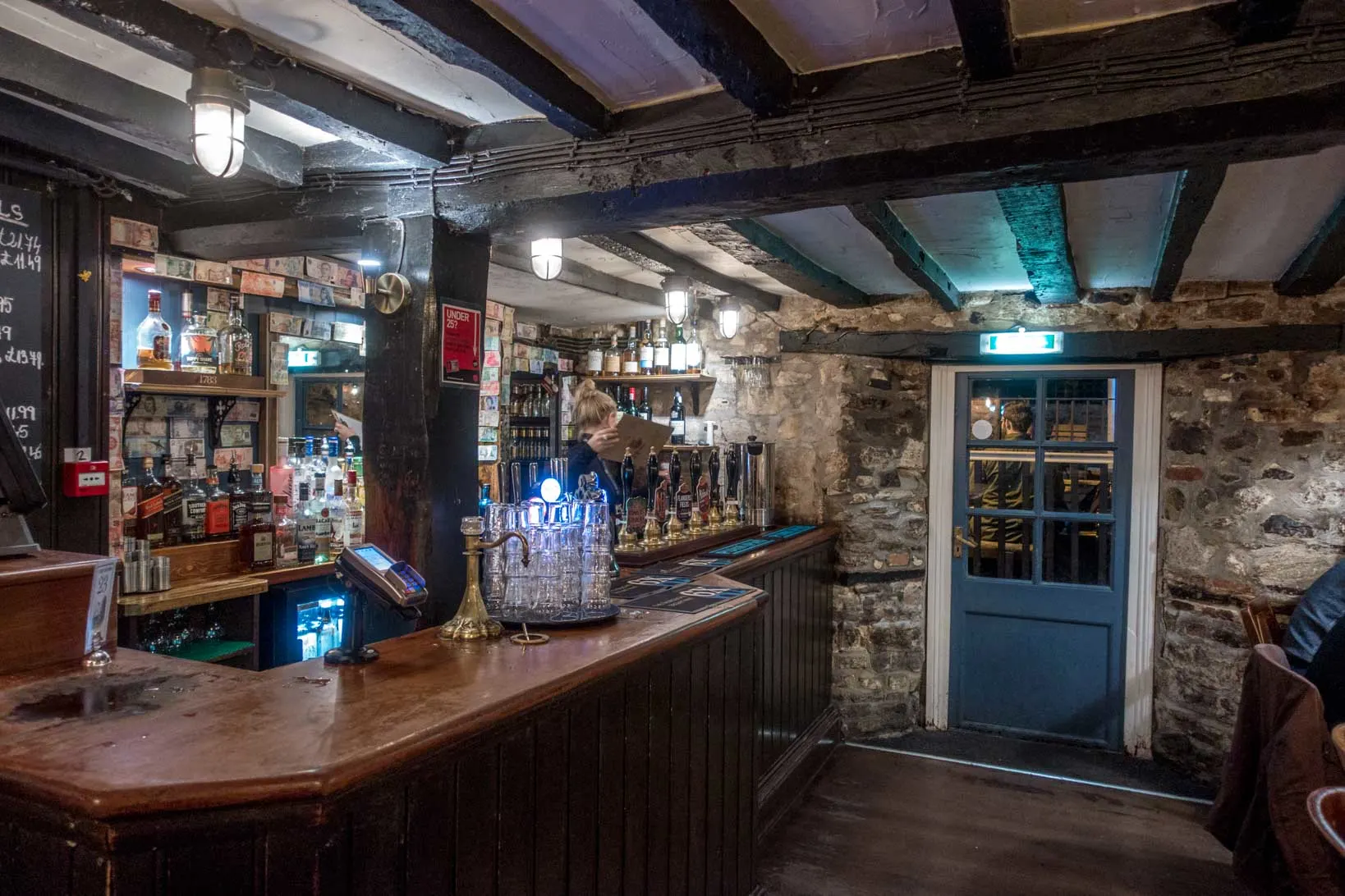 Bar, stone walls, and old wooden beams inside an historic pub.