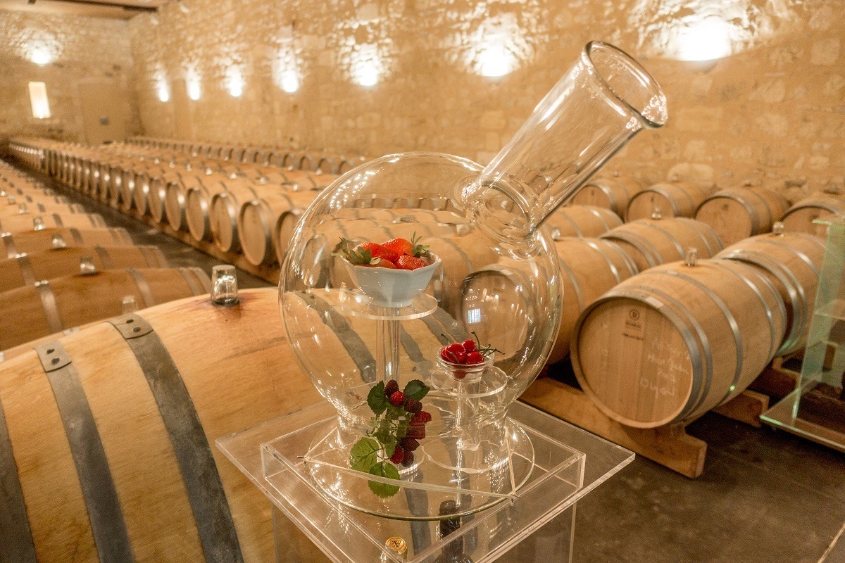 Wine barrel room with a close up of a glass jar filled with fruit
