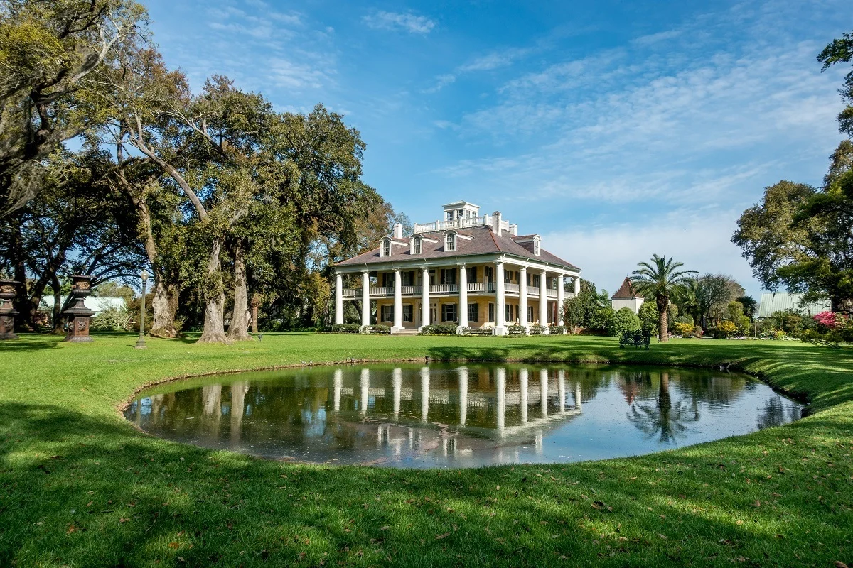 White columned mansion beside a small pond. 