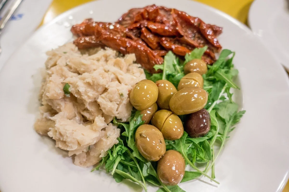 Plate with sundried tomatoes, olives, and a bean spread known as bigilla.