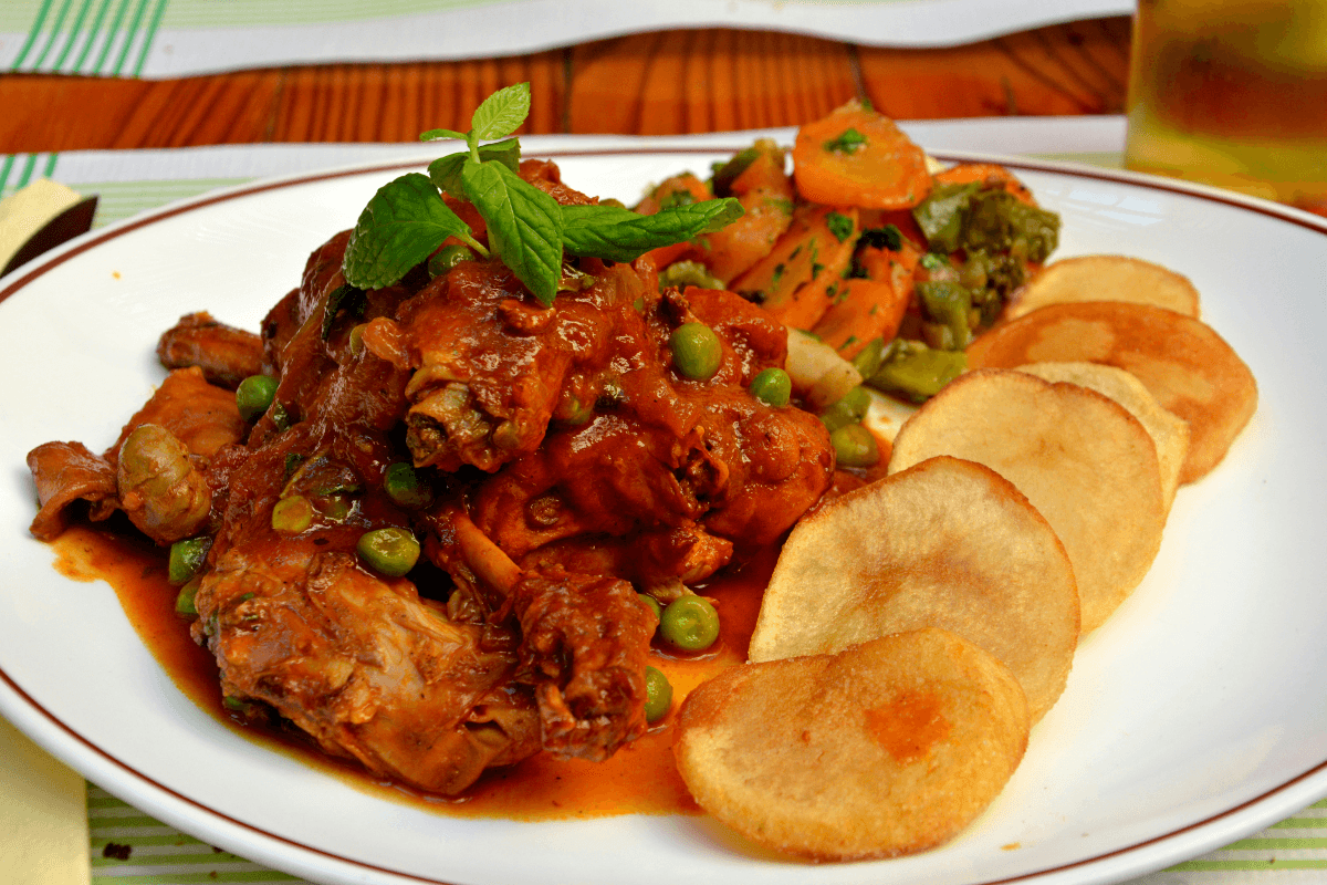 Stewed rabbit served with fried potatoes and vegetables.