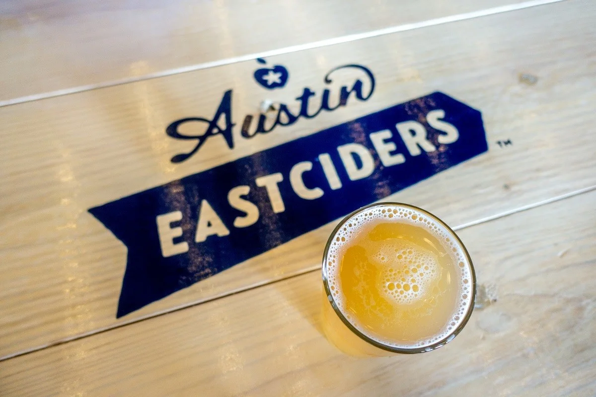 Pint of cider on table with Austin Eastciders logo