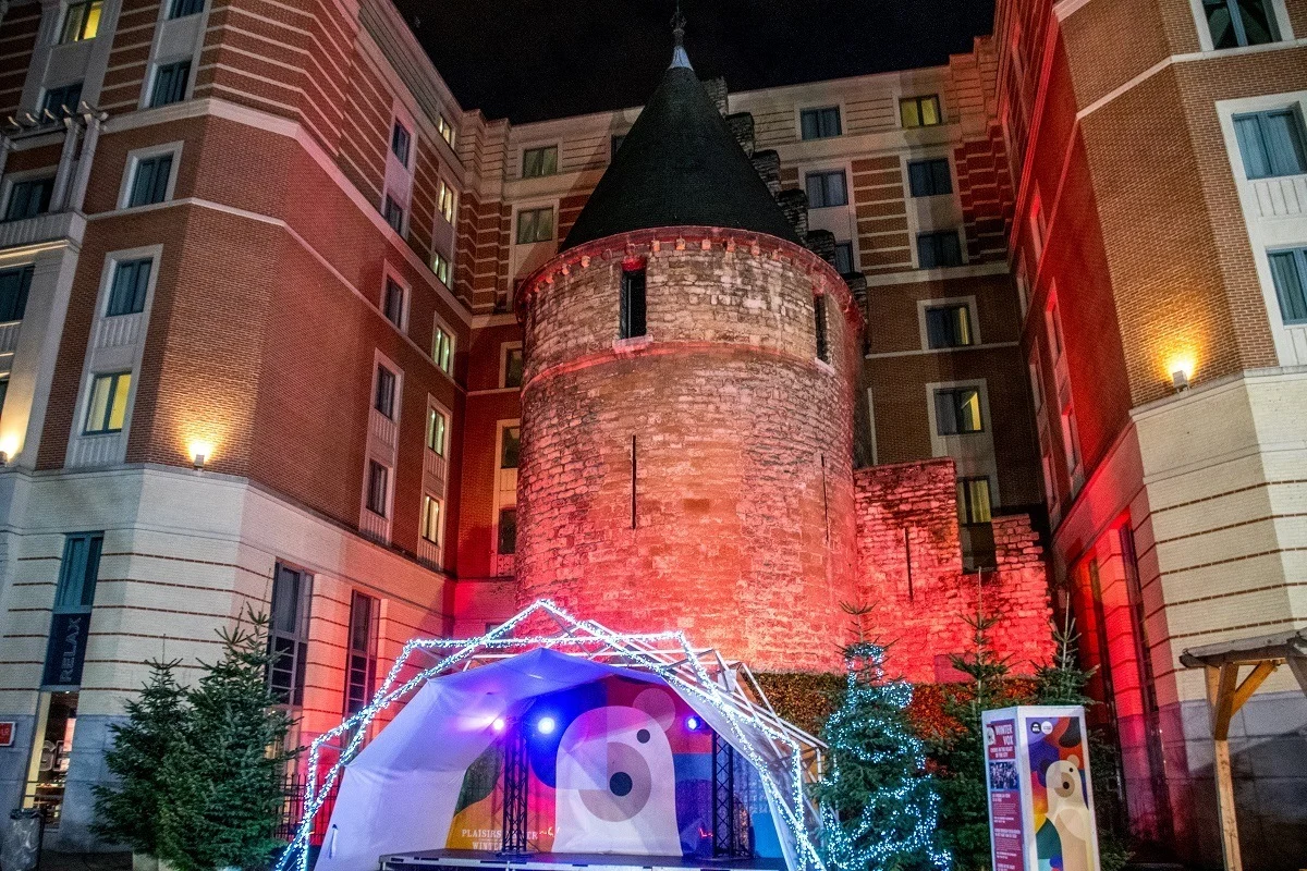 Stage in front of medieval tower surrounded by modern building 