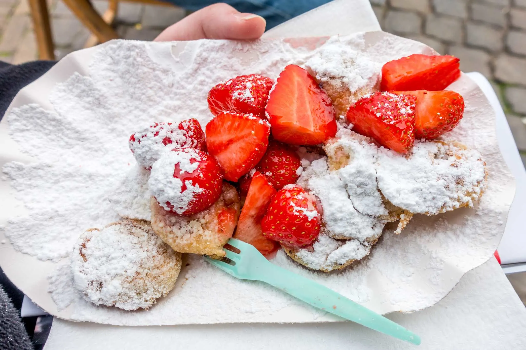Small pancakes topped with powdered sugar and strawberries