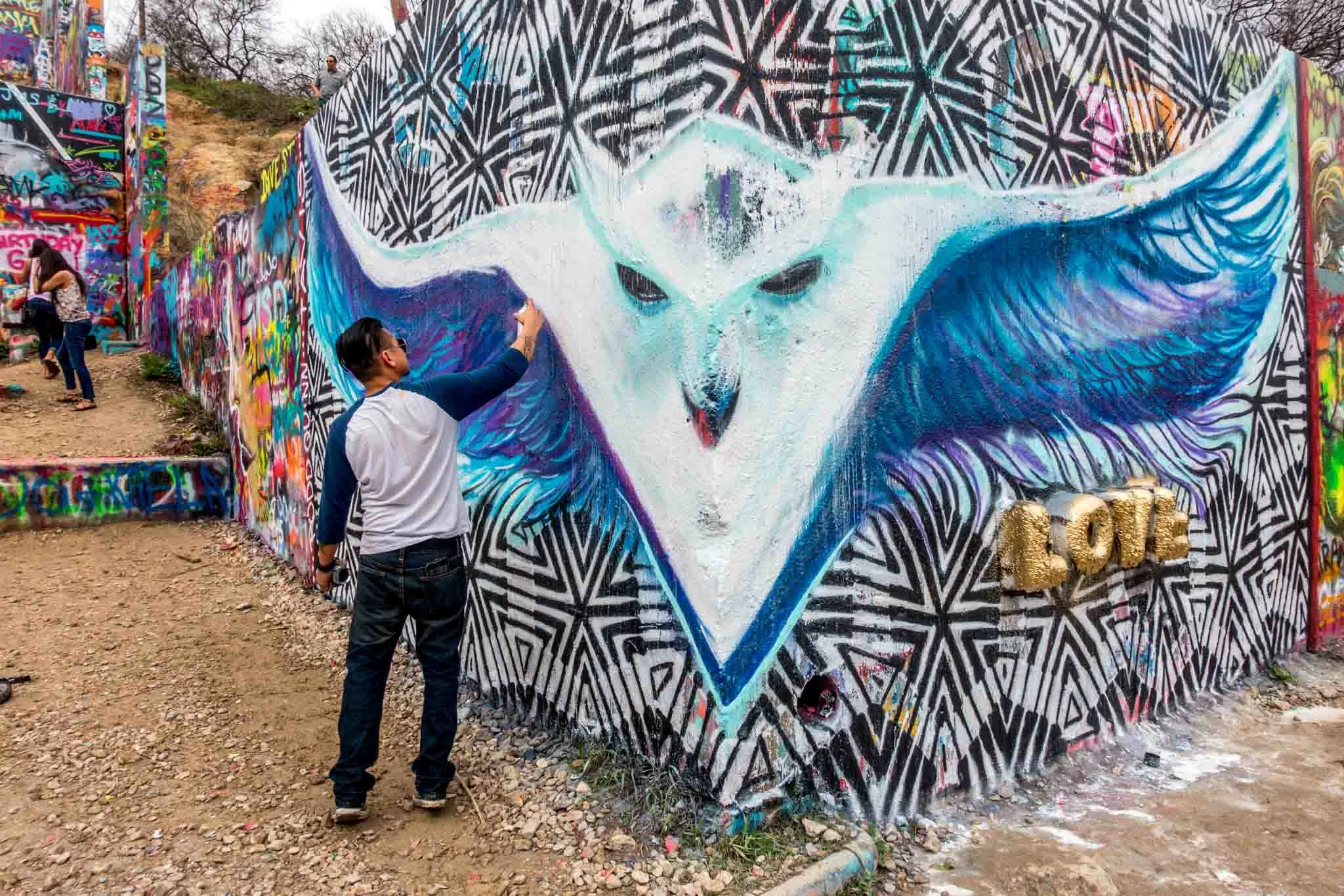 Artist spray painting a white design at HOPE Outdoor Gallery