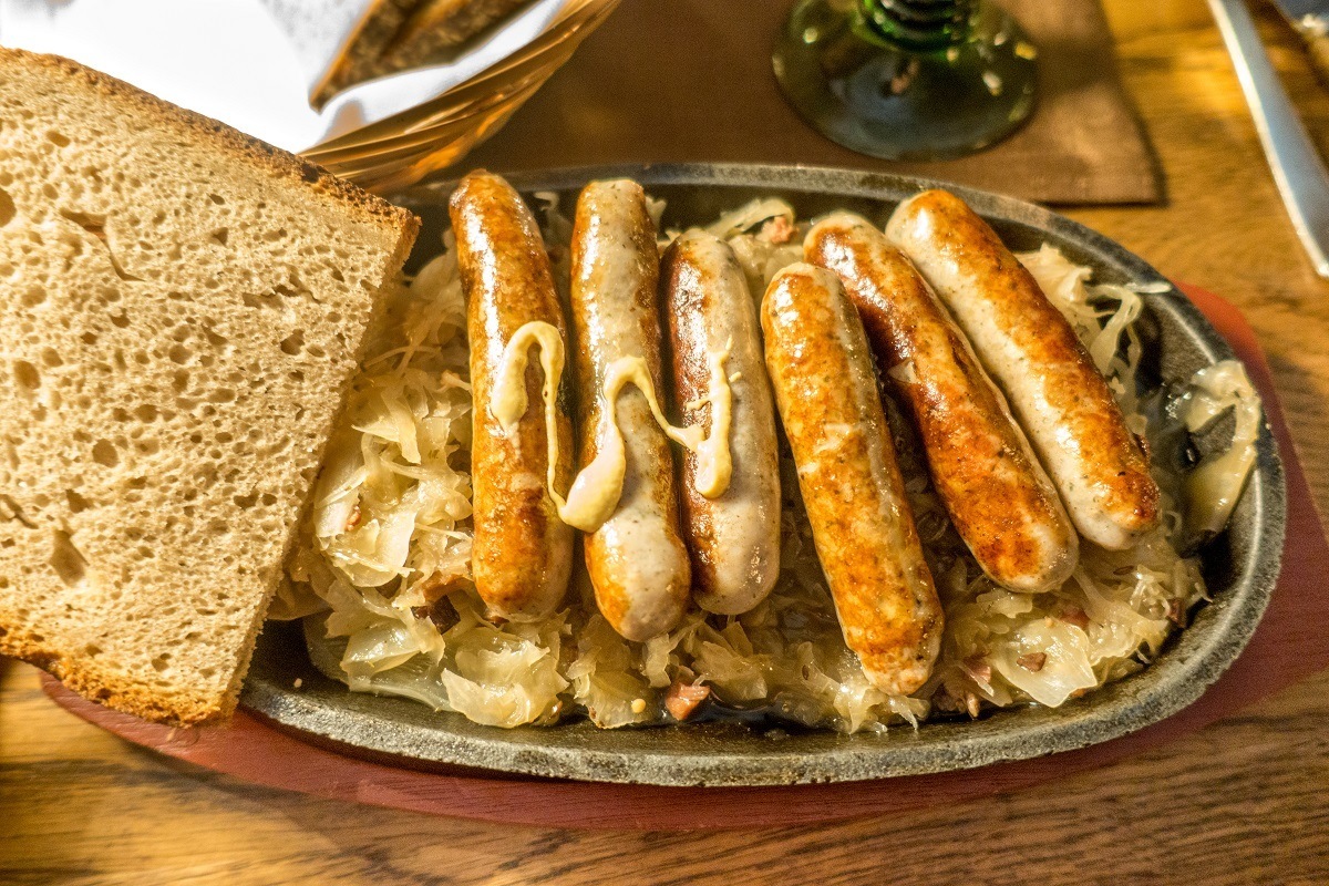 Small Nuremberger sausages served on a pewter plate with sauerkraut and bread