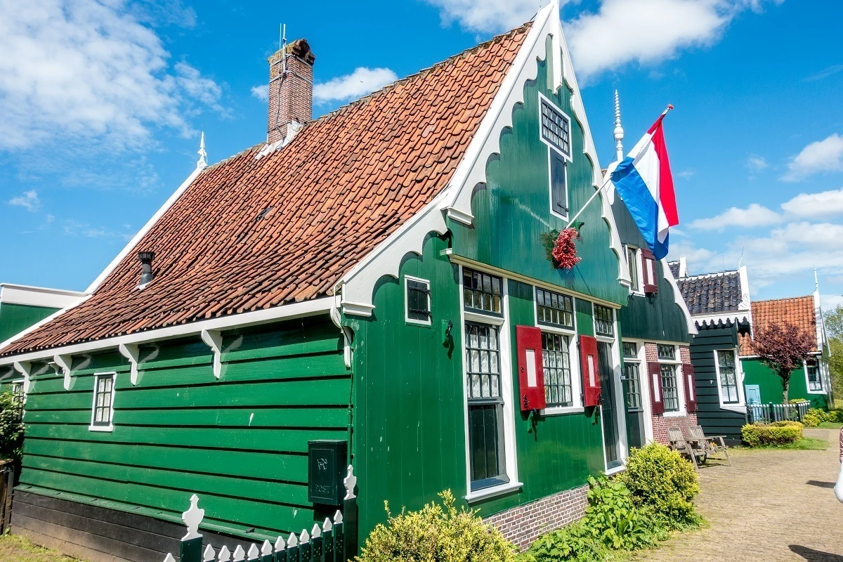 Traditional green Zaans houses flying Dutch national flag