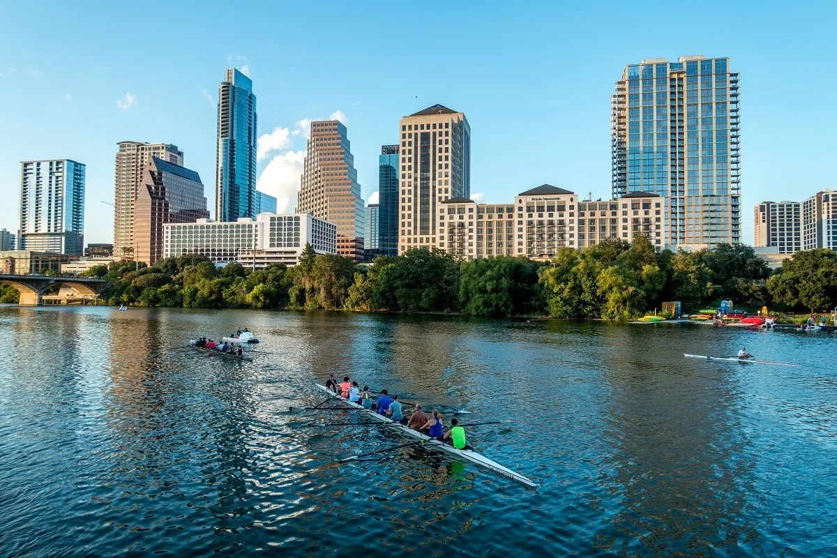 People rowing on Lady Bird Lake with buildings in the background 