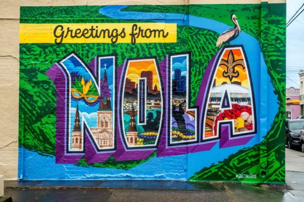 Street art mural that says "Greetings from NOLA" and features scenes from New Orleans