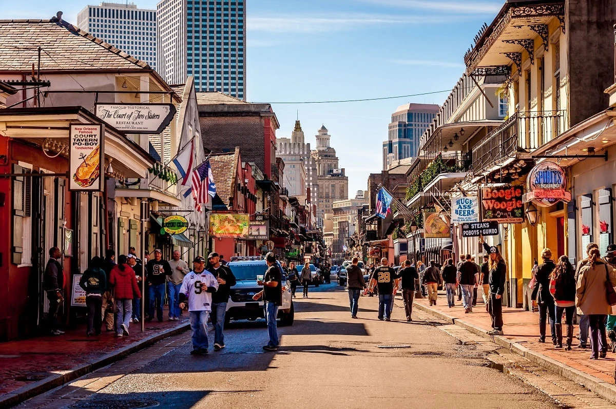 People strolling by the bars on Bourbon Street.