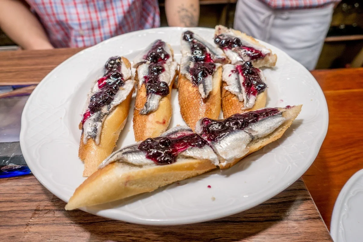 Anchovies topped with blueberry jam on a plate