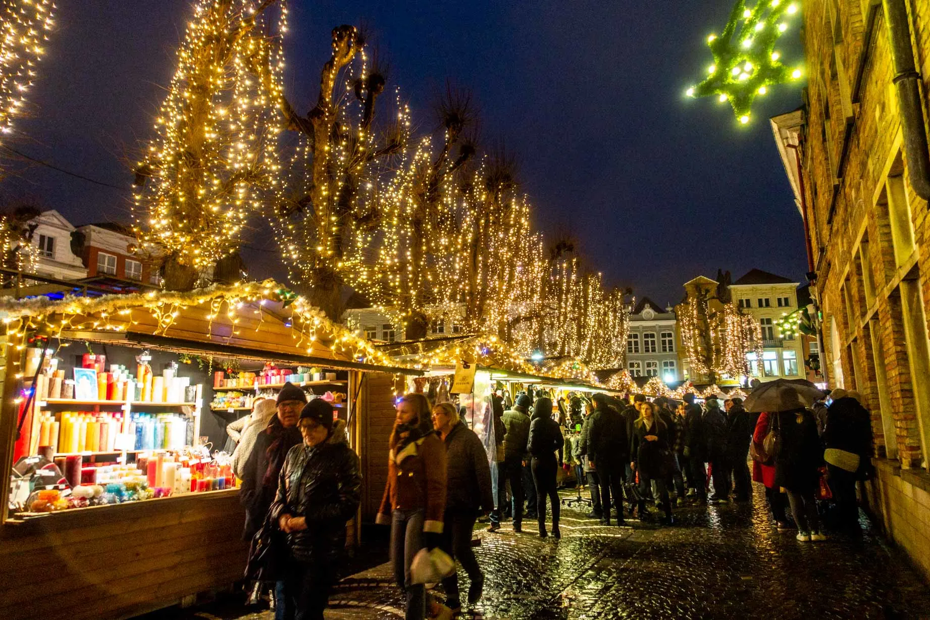 Shoppers at the market stalls decorated with Christmas lights