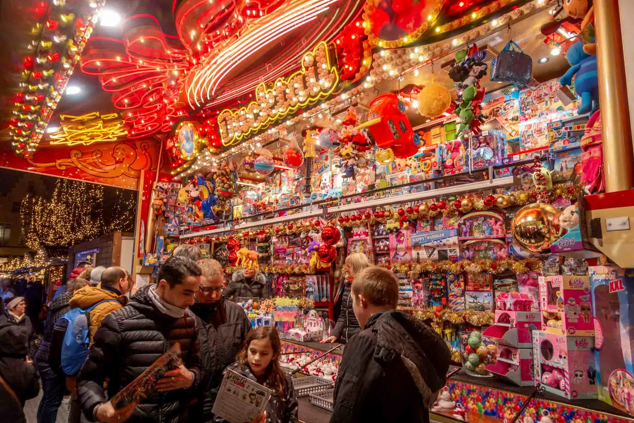 People shopping for toys at a brightly lit kiosk