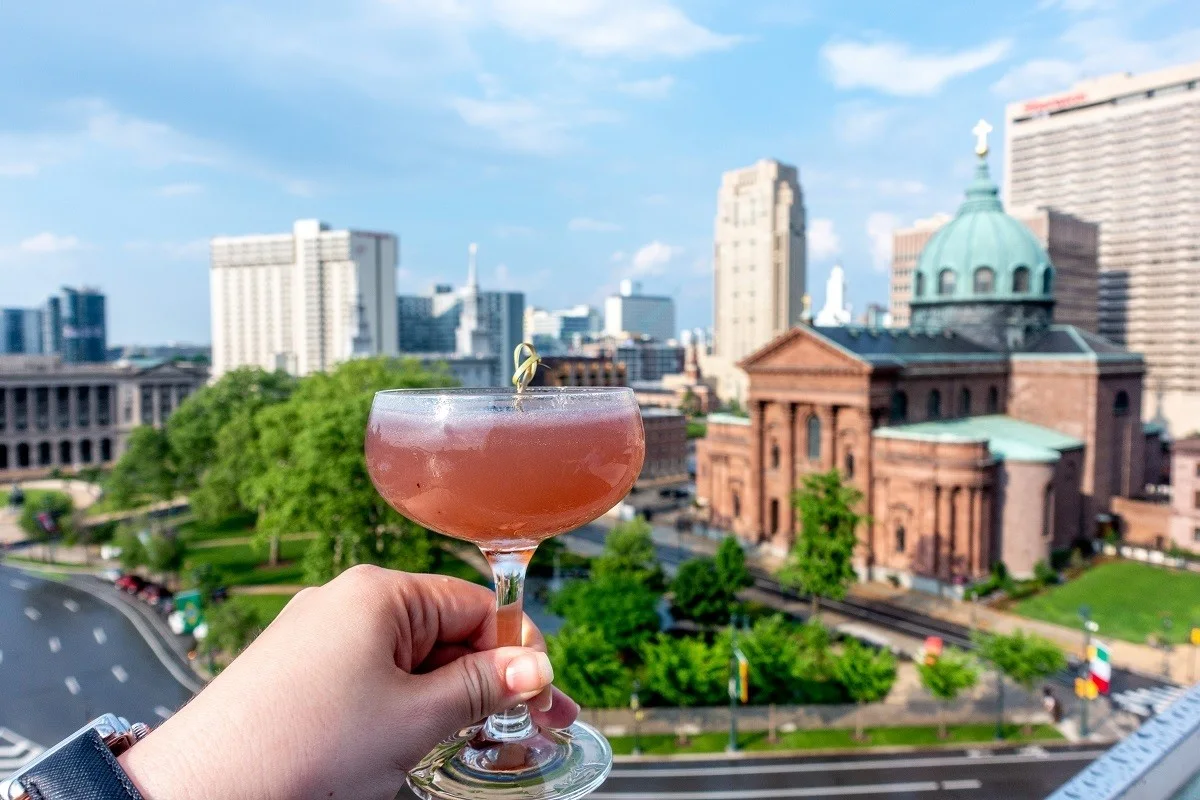 Cocktail glass in front of a skyline view of a church and buildings