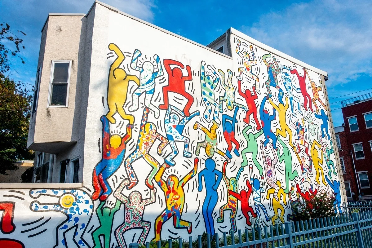 Colorful cartoon people on street art mural by Keith Haring