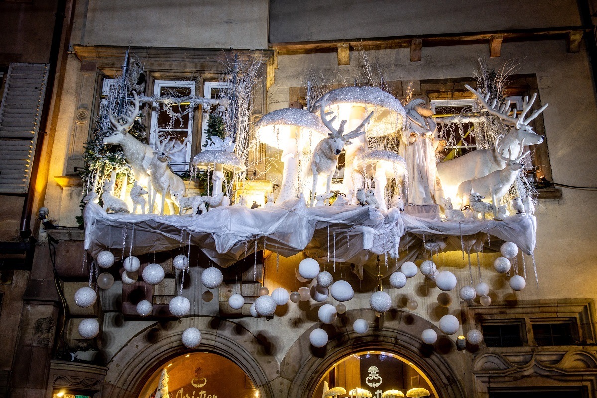 Christmas display with reindeer and ornaments on a storefront.