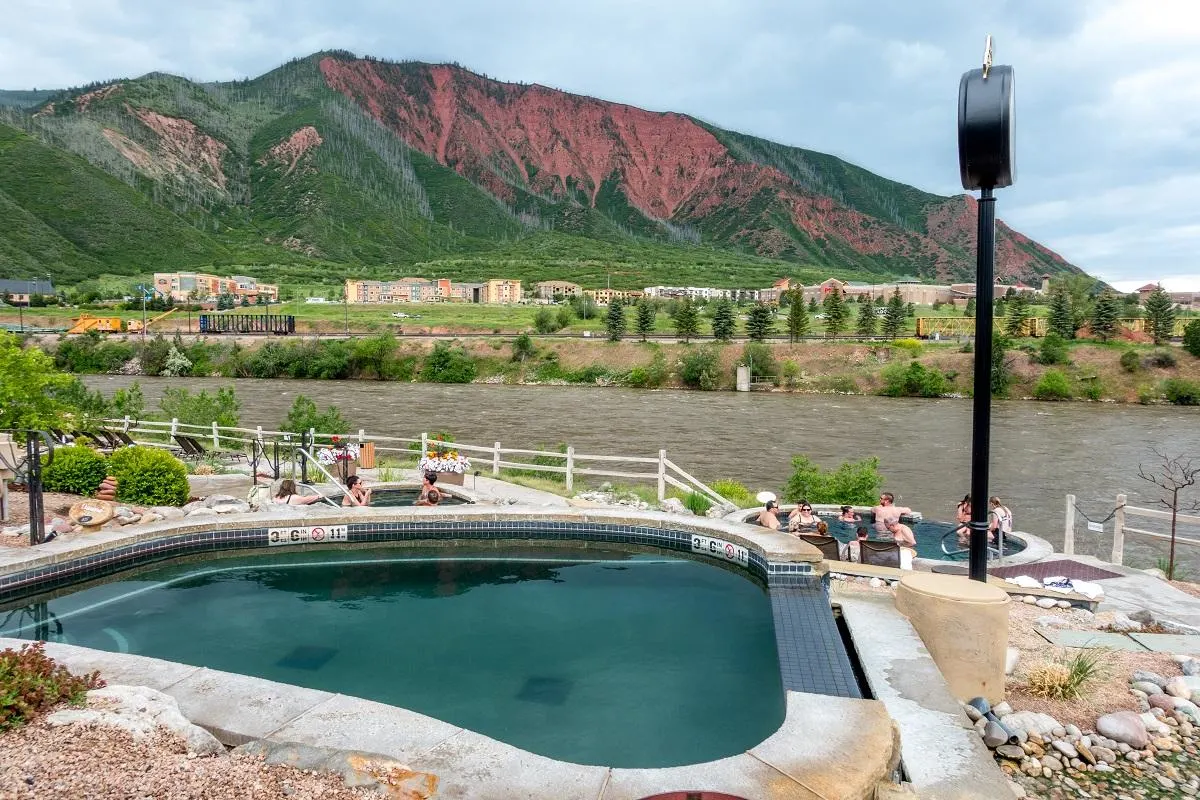 Hot springs pool near a river with red mountain in background
