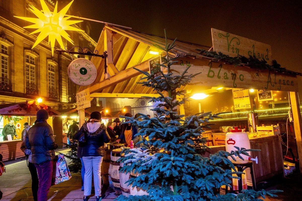 People at a wooden chalet selling mulled wine