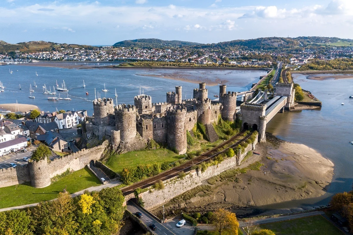 Overhead view of a medieval castle with numerous towers, its drawbridge, and harbor