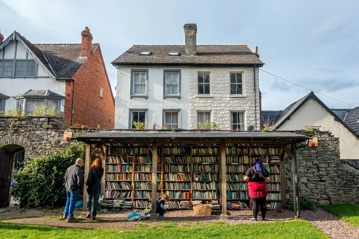 People browsing bookshelves outdoors in Hay-on-Wye