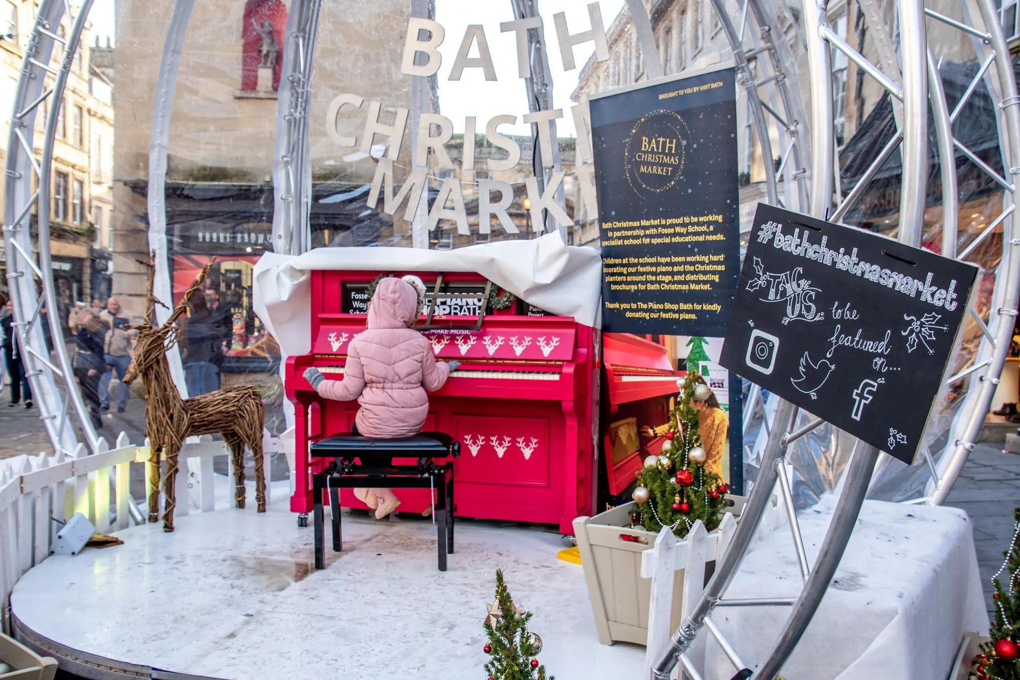 Girl in pink coat playing piano outside