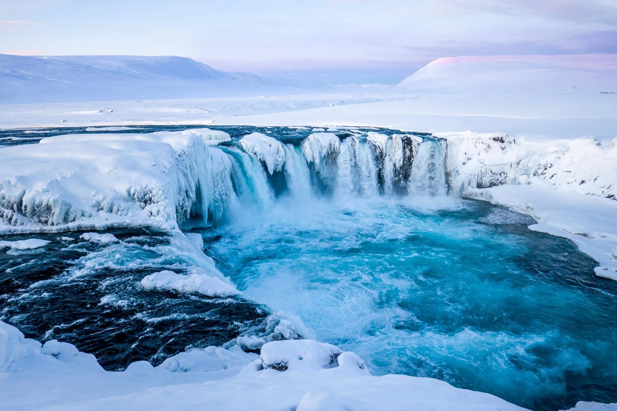 The Godafoss waterfall in the winter with snow and ice at sunrise.