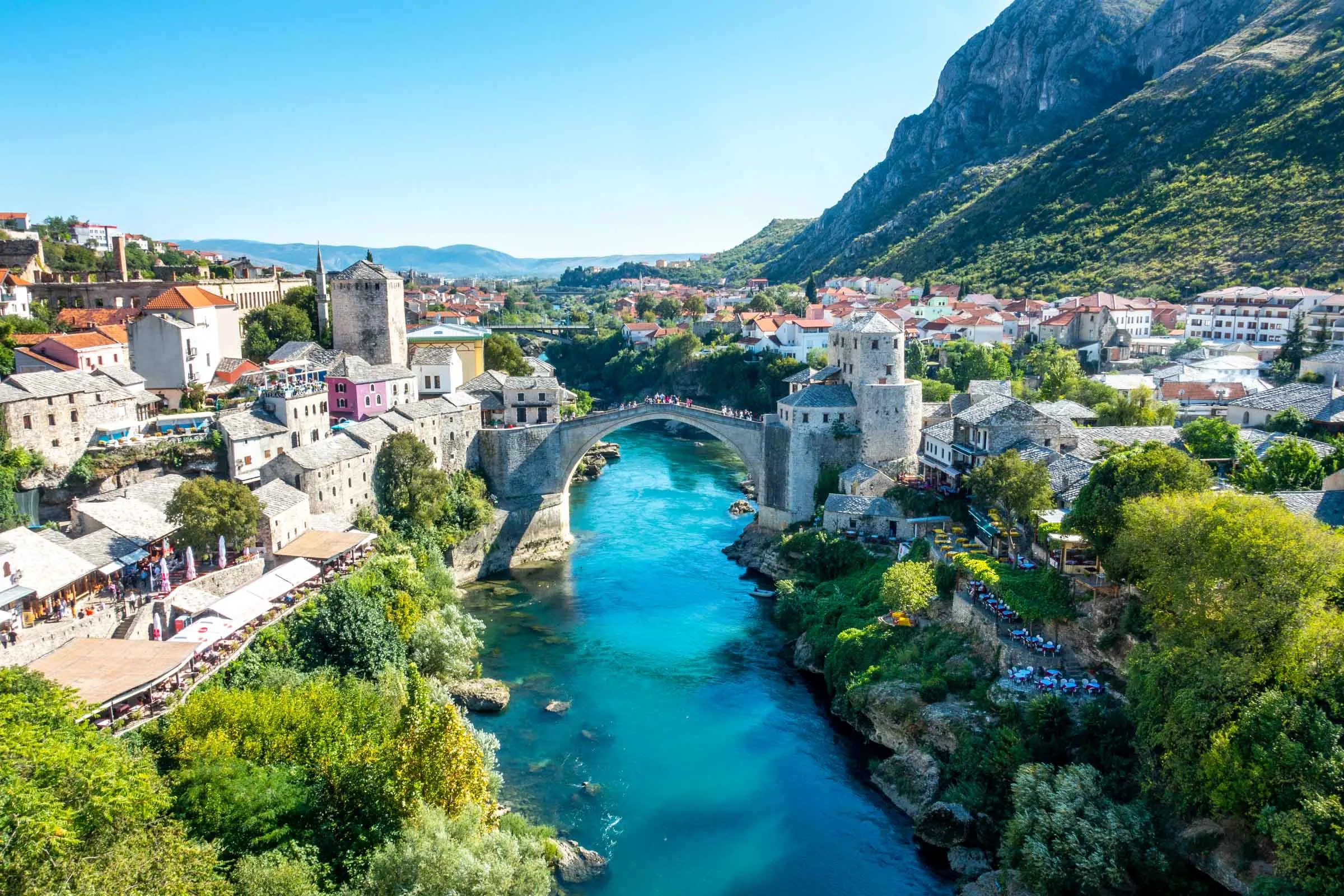 Stone bridge (Stari Most) over a river with buildings on both riverbanks  