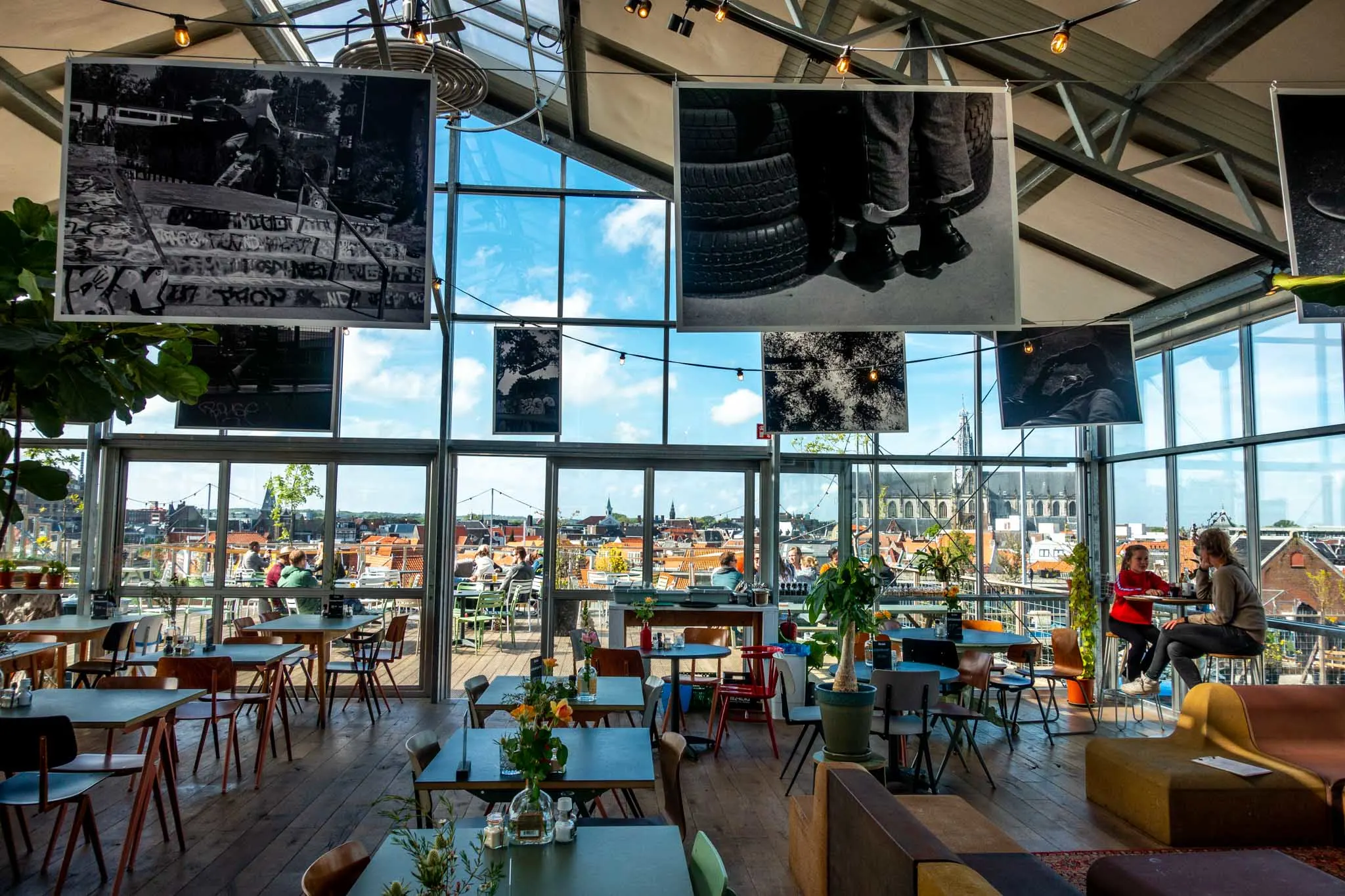 Tables inside a rooftop cafe with glass walls and a view over the city