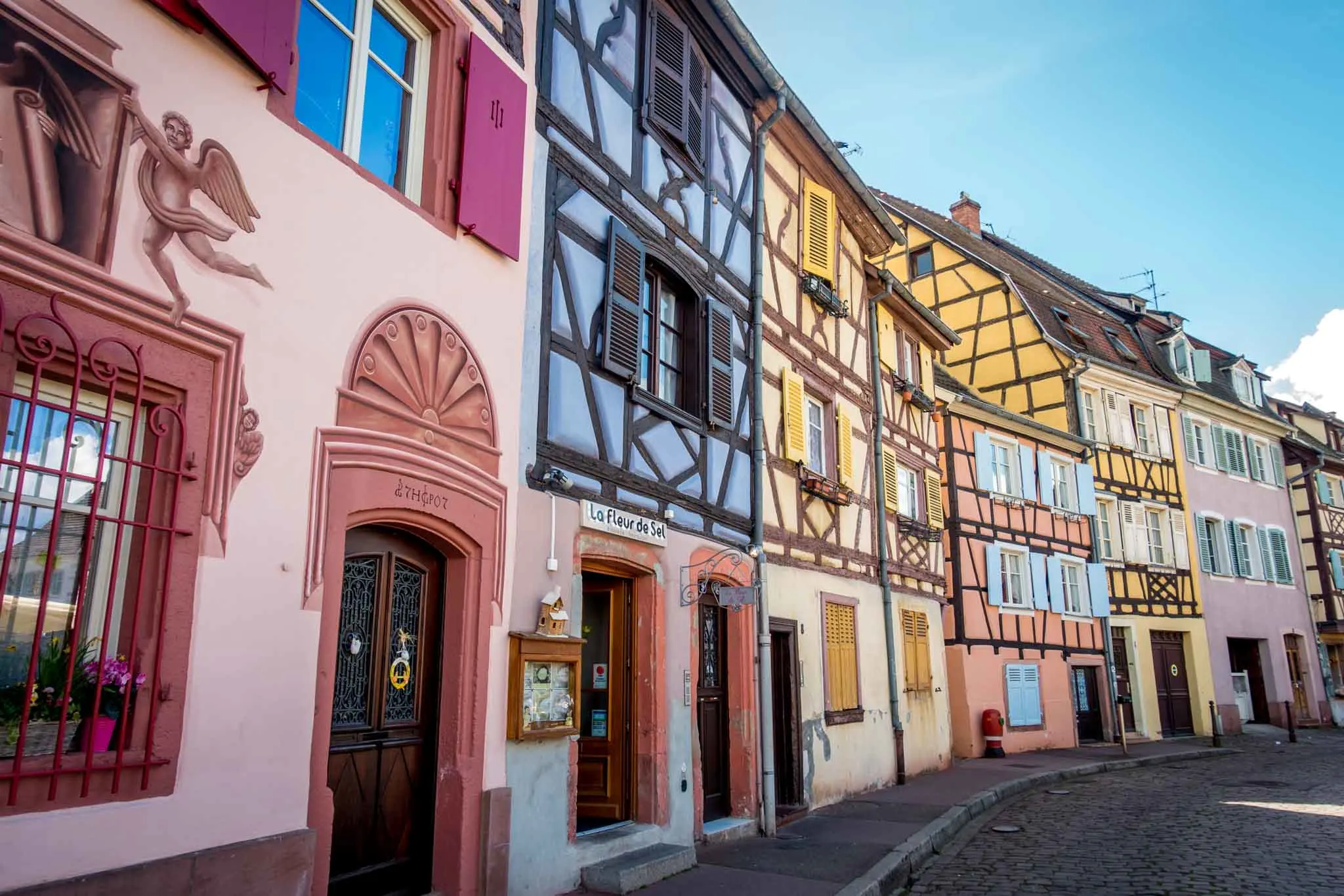 Row of half-timbered buildings painted pink, purple, and yellow