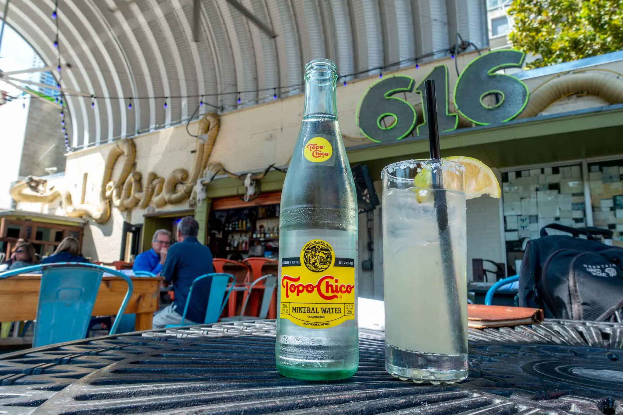 Bottle of Topo Chico next to a glass with a slice of lime