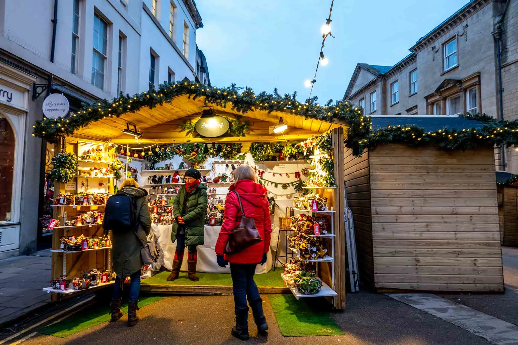 Shoppers at a wooden stall shopping for Christmas gifts.