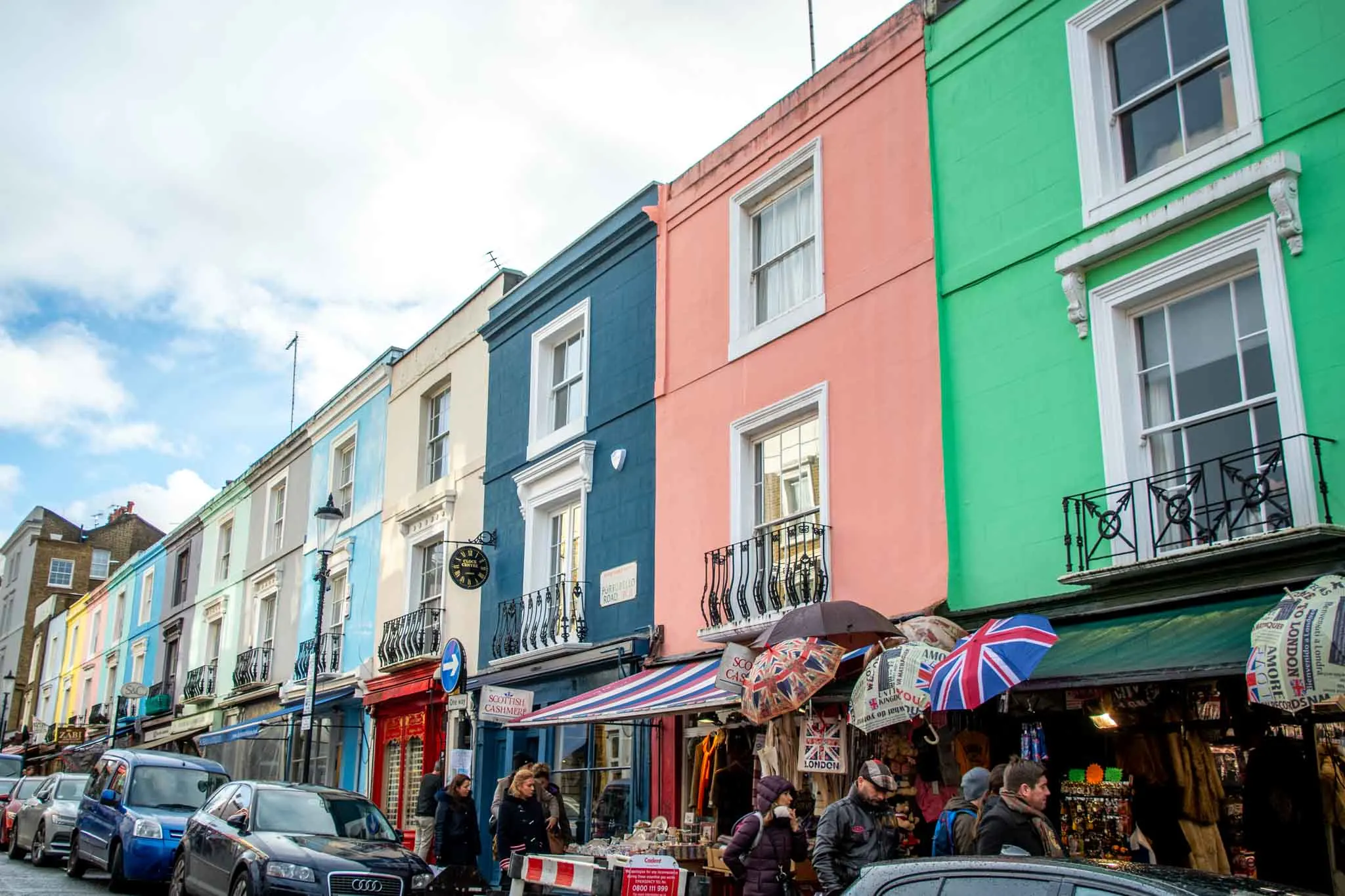 People walking by a row of colorful buildings on Portobello Road in Notting Hill