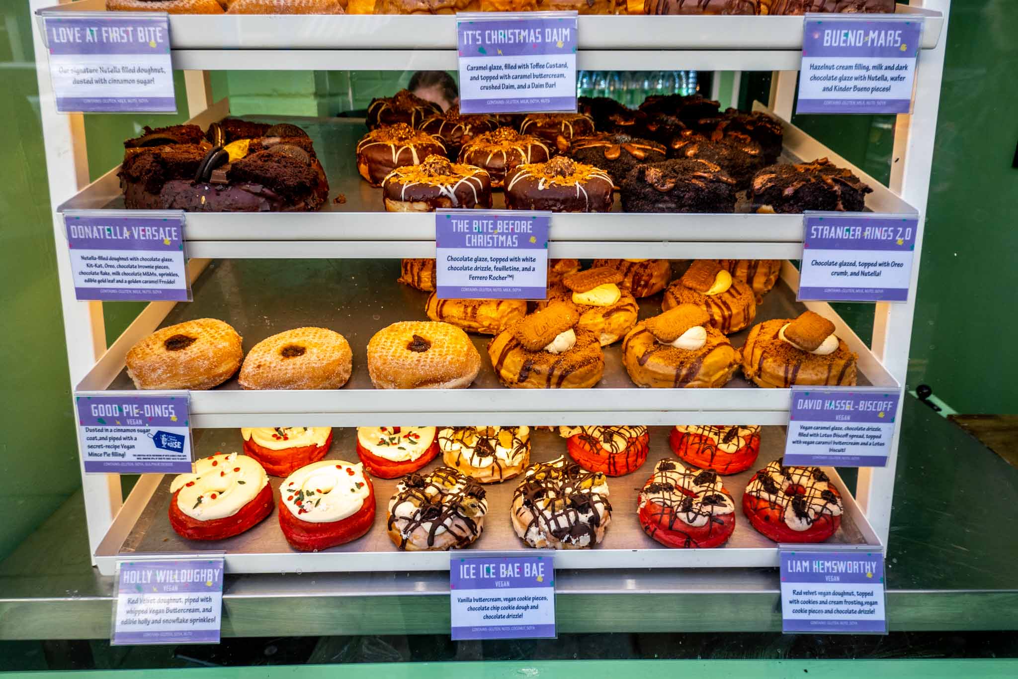 Shelves displaying decadent donuts with unusual names and flavors