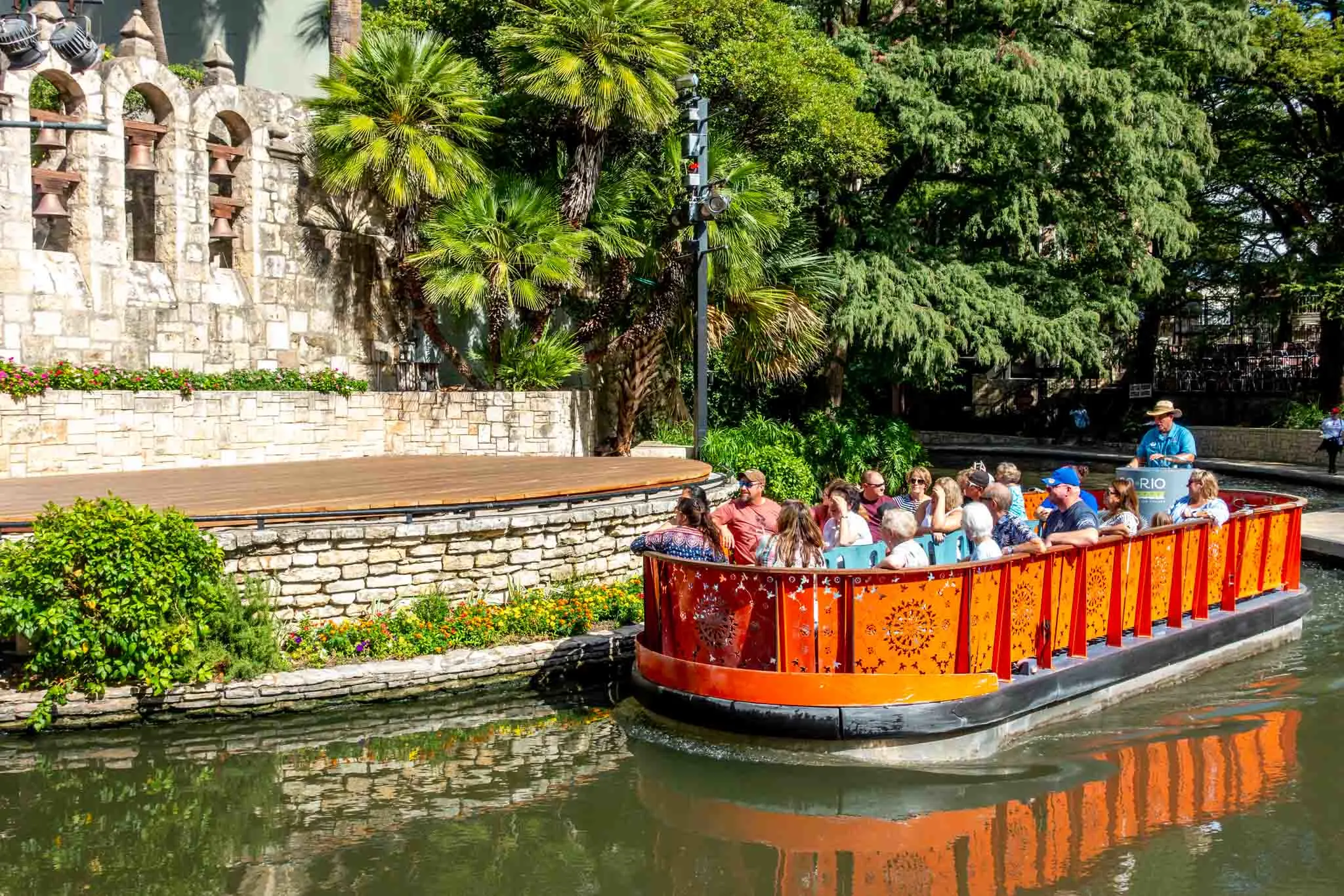 People in an orange barge cruising the river on a weekend in San Antonio Texas.