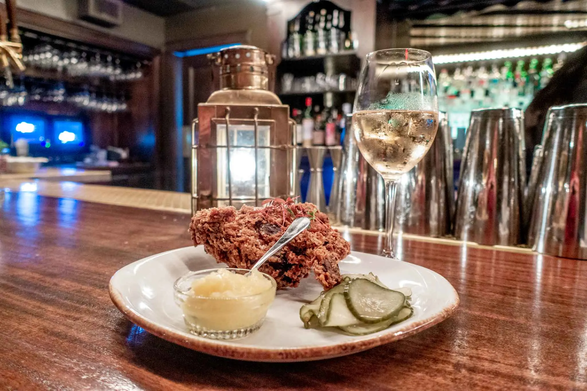 Fried chicken and pickles on a plate with a glass of champagne