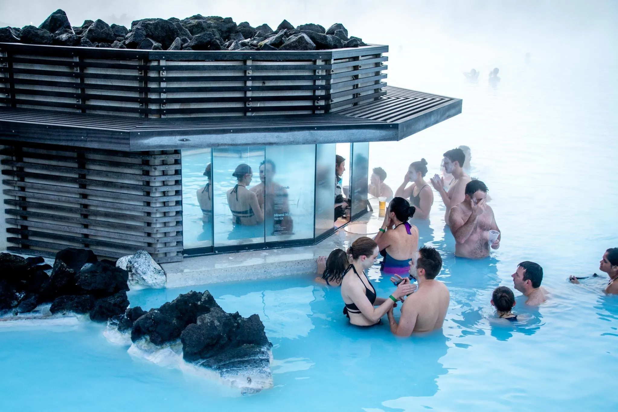 People applying silica face masks standing in milky blue water