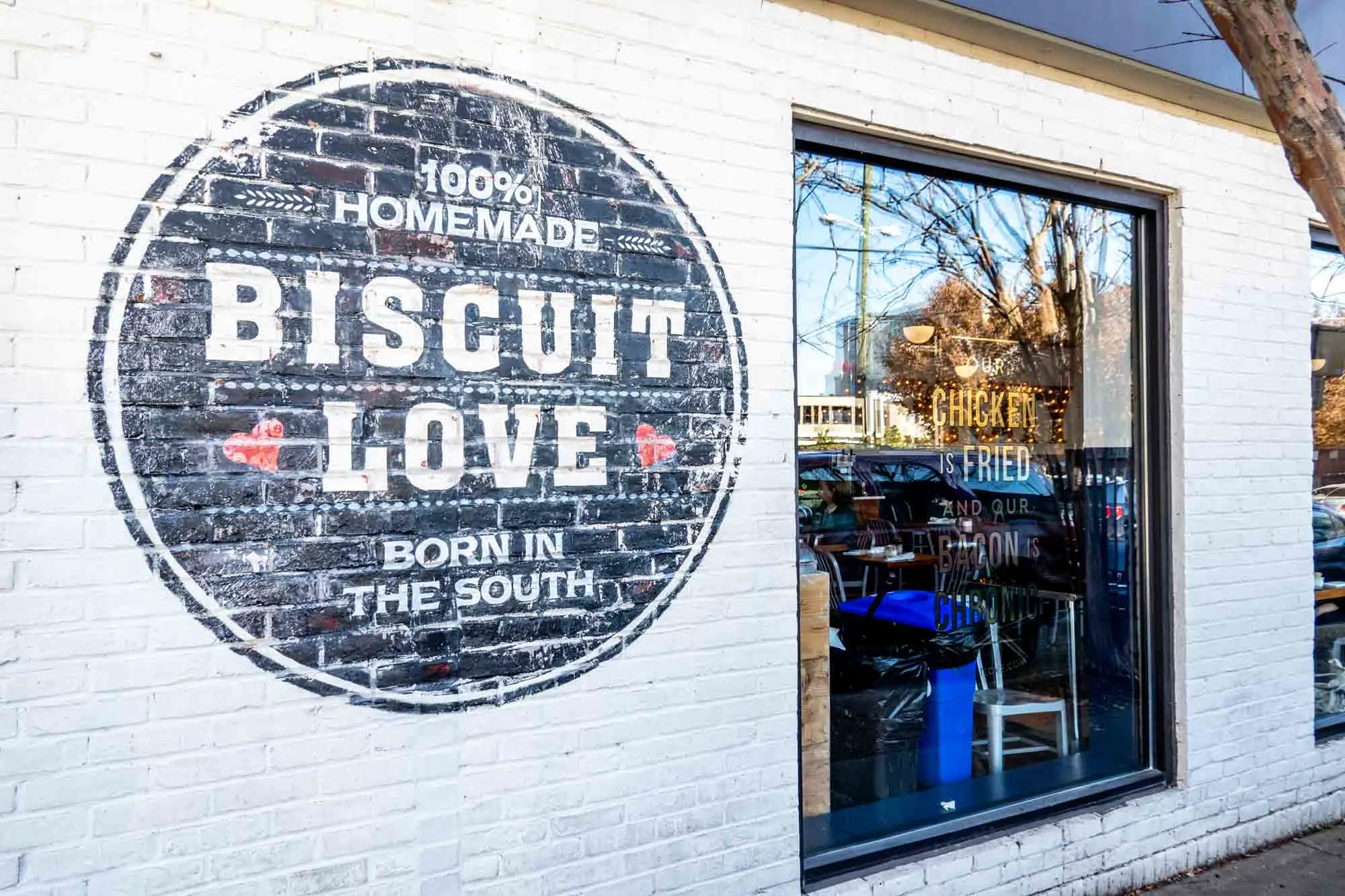White brick building with a painted sign: Biscuit Love, 100% Homemade, Born in the South