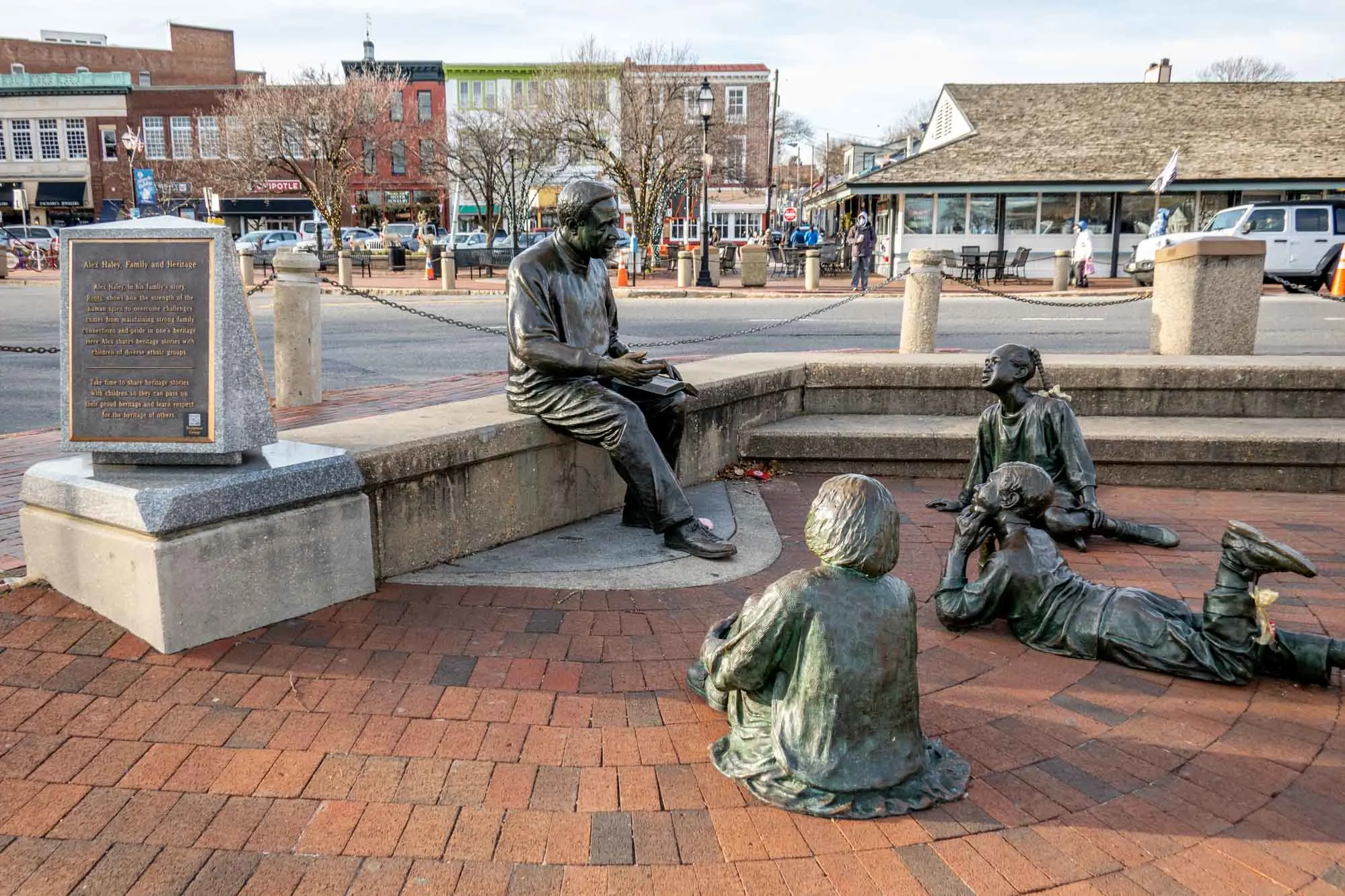 Sculpture of a man reading to three children