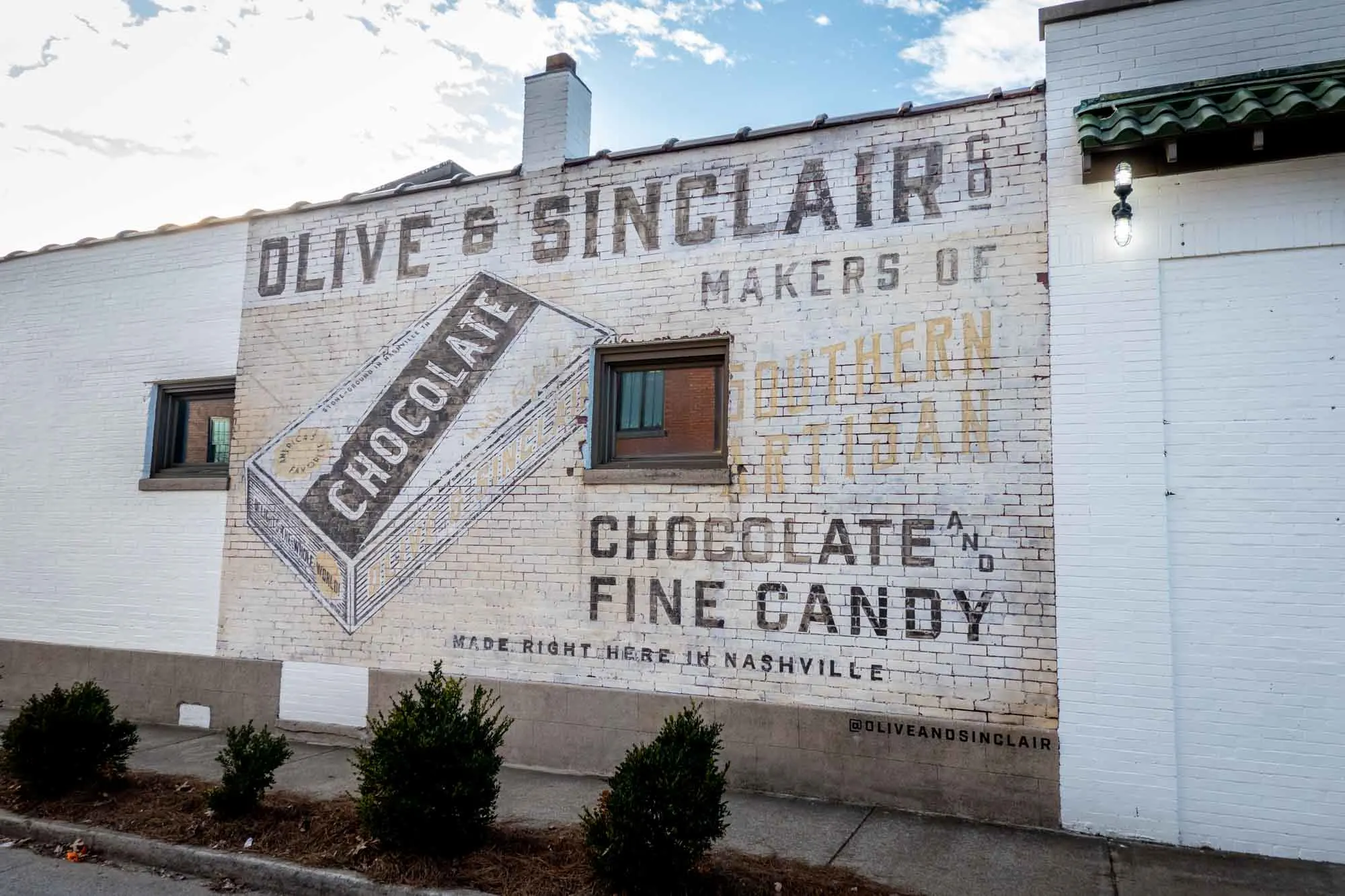 White brick wall painted with an old fashioned advertisement for "Olive & Sinclair Co., Makers of Southern Artisam Chocolate and Fine Candy Made Right Here in Nashville."