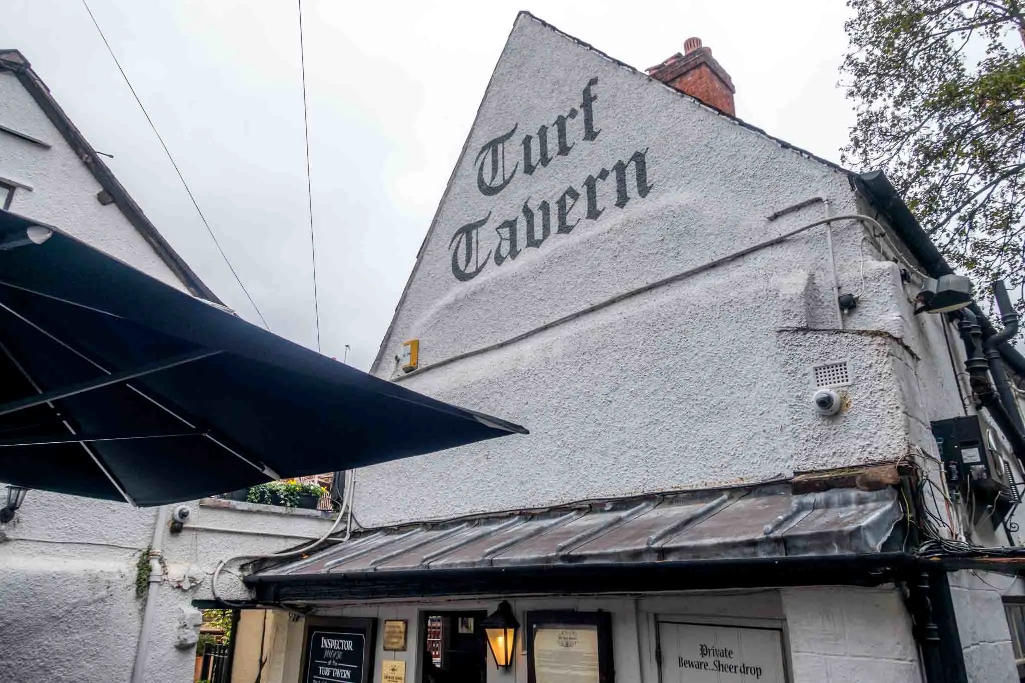 Exterior of a white stucco building with a black sign for Turf Tavern