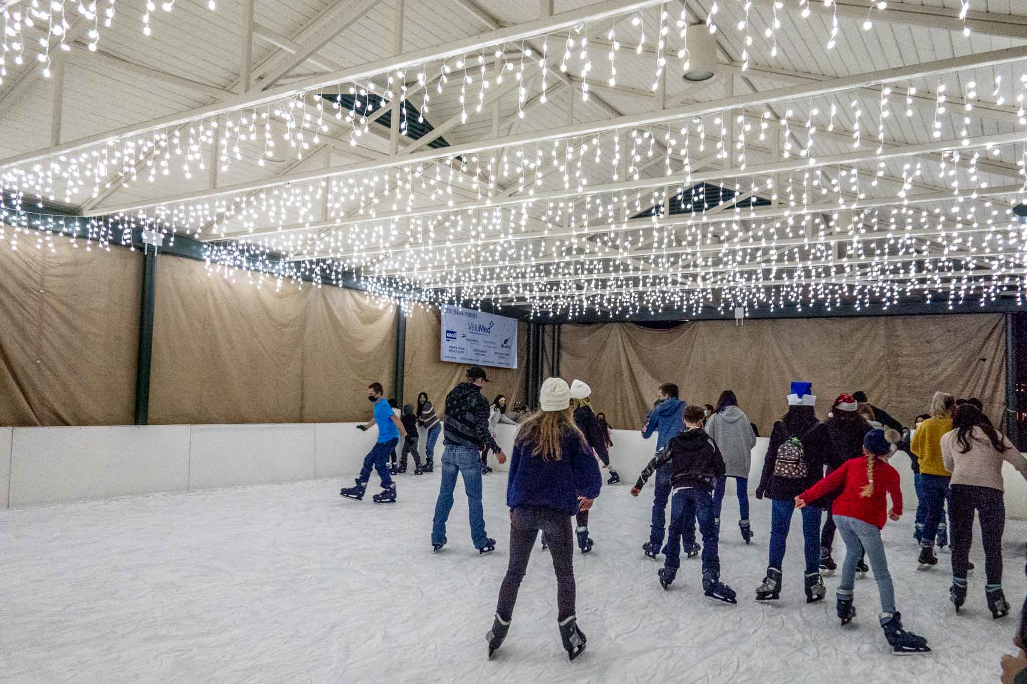 Children skating on an ice skating rink decorated with white lights