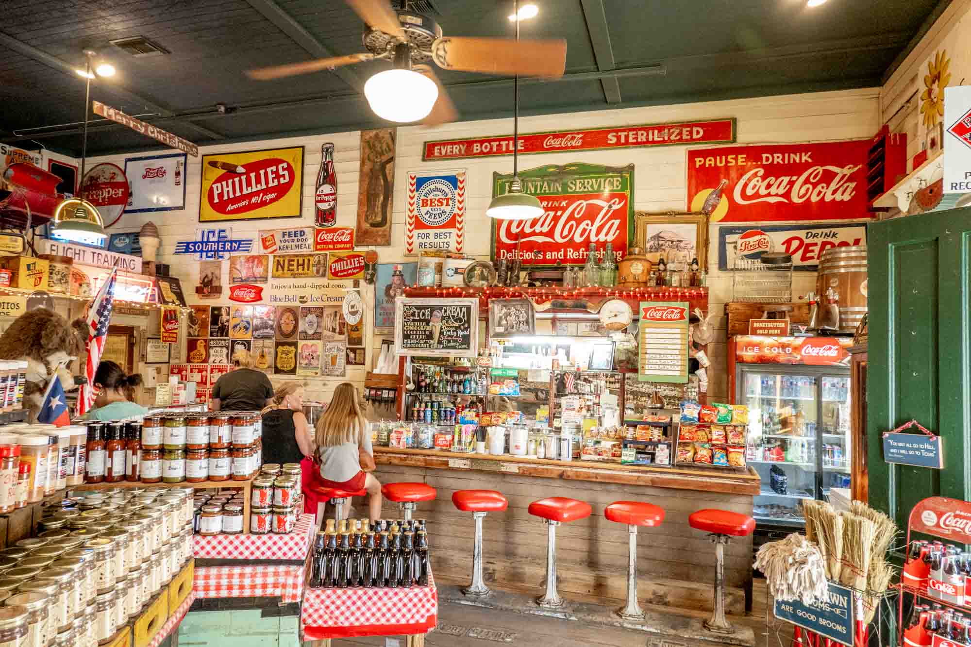 People sitting at a soda counter in front of a wall covered with old-fashioned signs 