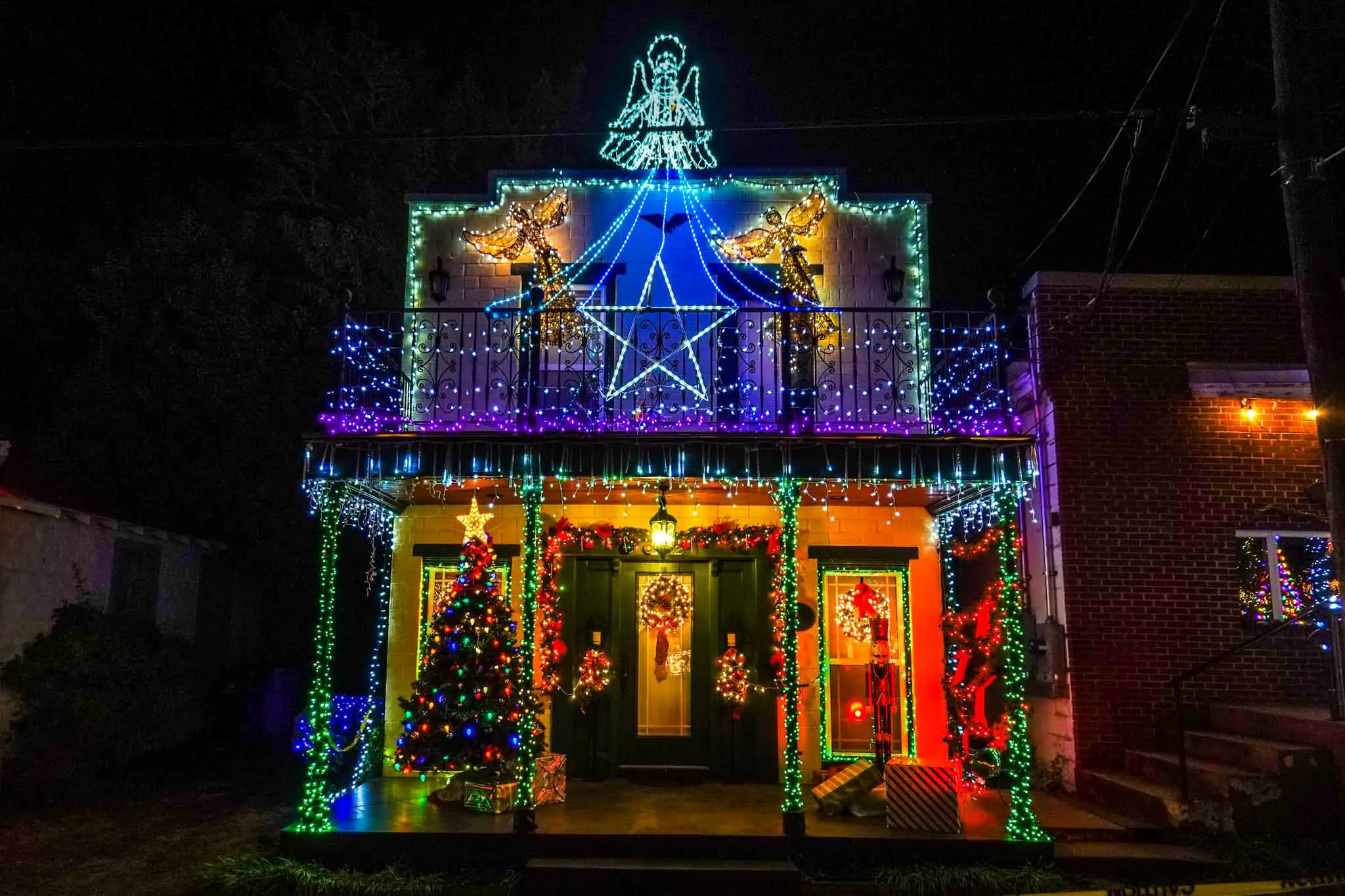 Building decorated with colorful Christmas lights and topped by an angel light sculpture