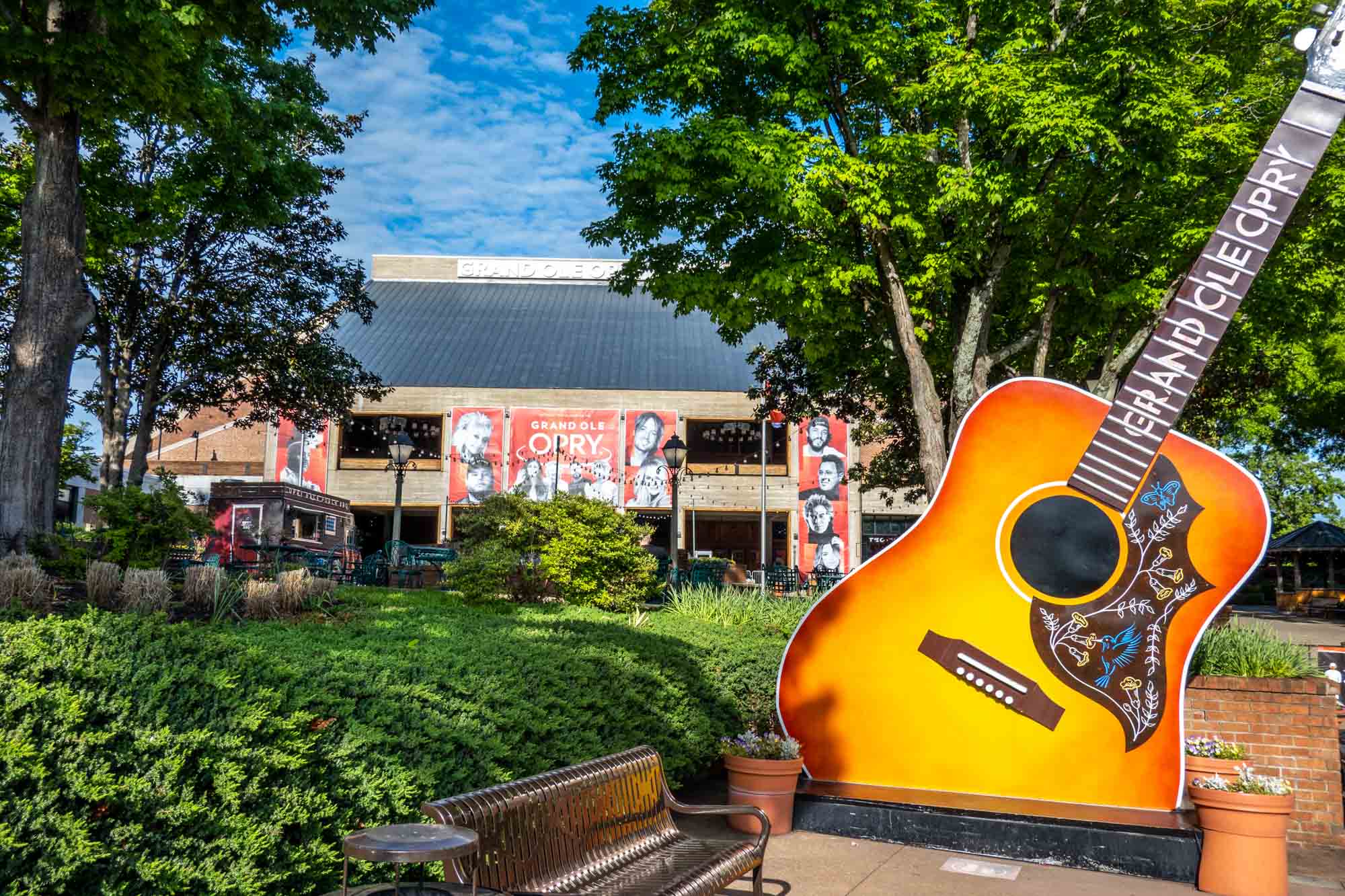 Large guitar sculpture in front of a large brick building with a sign for the Grand Ole Opry