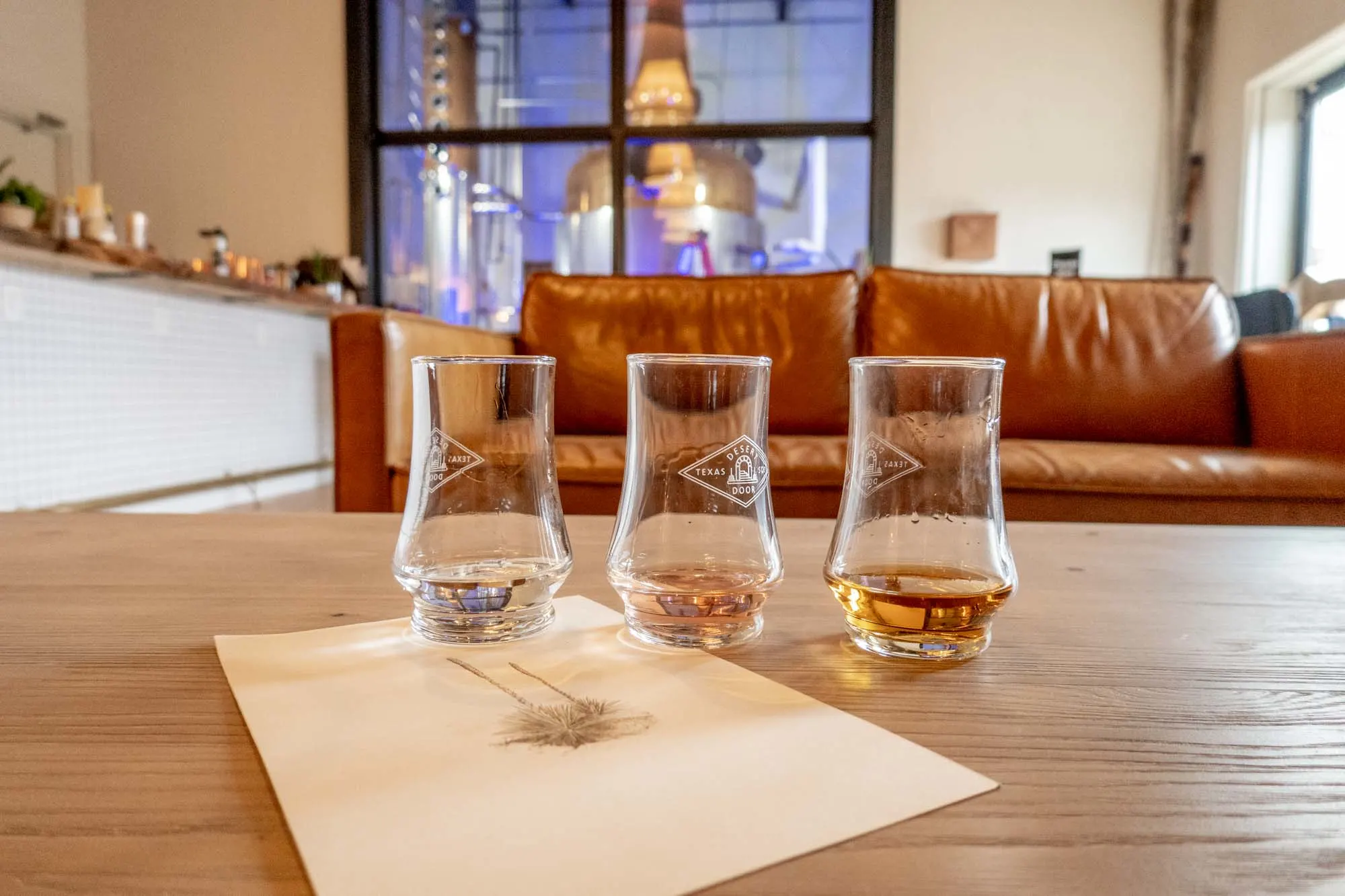 Three glasses of sotol on a table in a distillery.